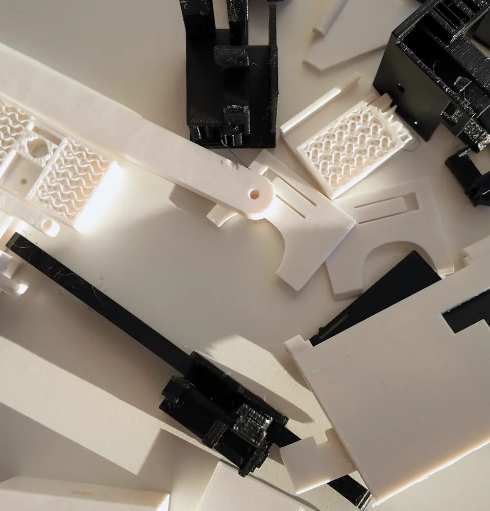 A pile of small 3D-printed test pieces in black and white on a desk.