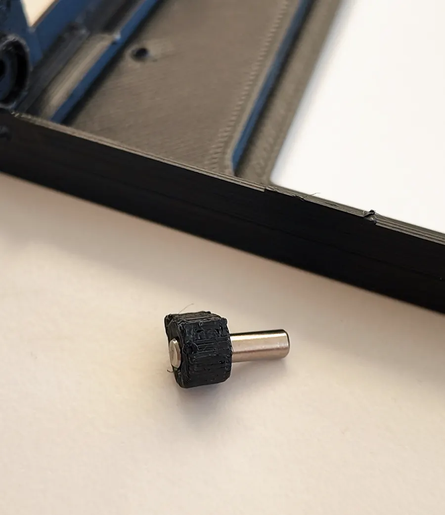 A snapped hinge piece lying next to the black glass frame.